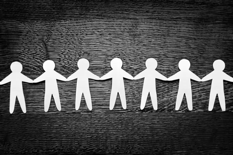 Cutout paper people on wooden table and artistic shadows